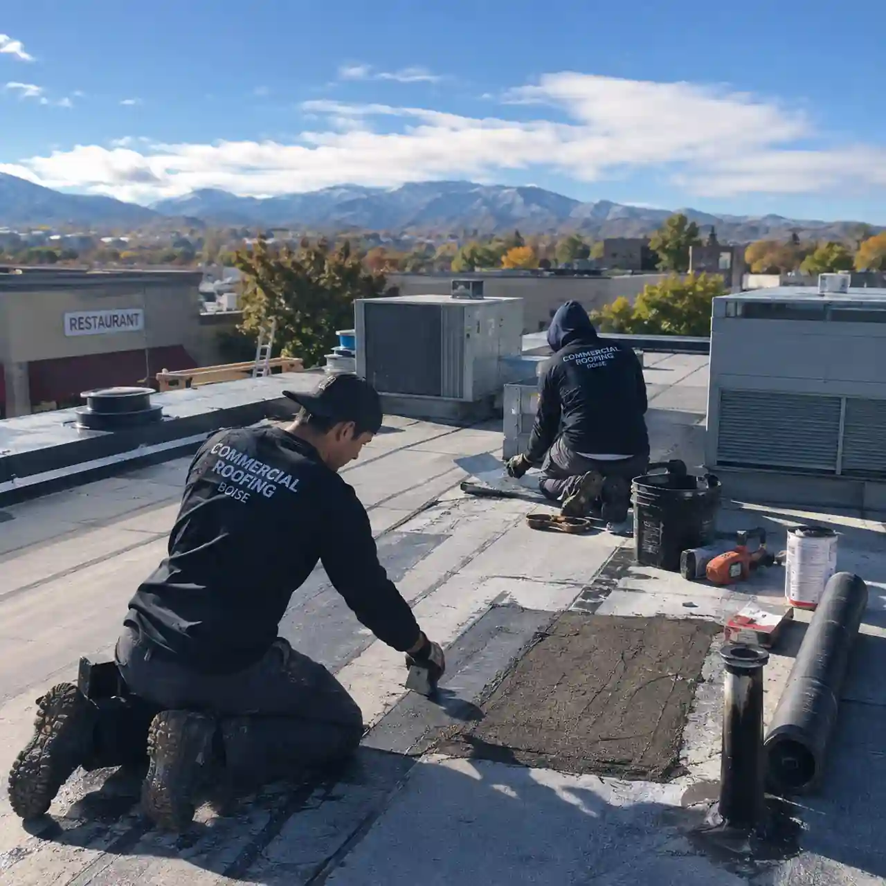 Emergency roof repair crew patching a commercial roof section in Boise